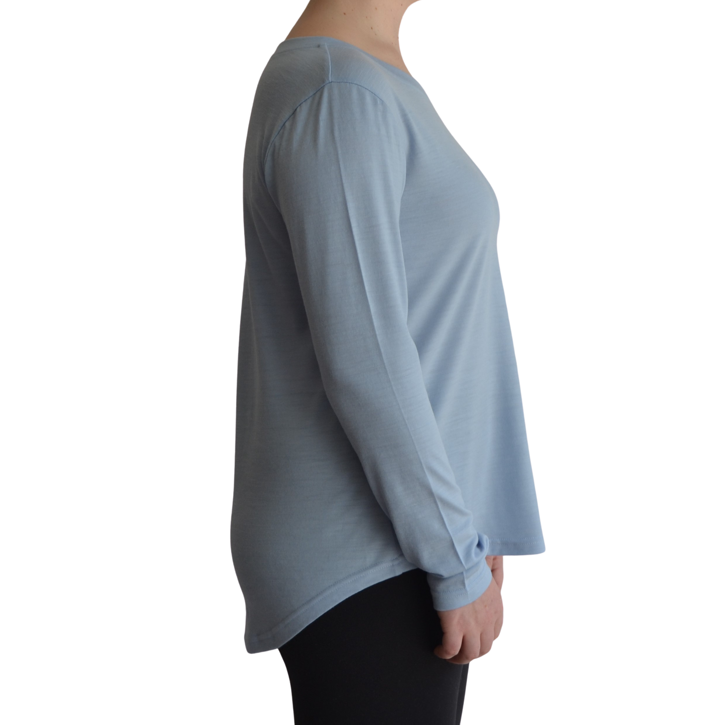 Links long sleeve merino top in ice blue colour, model is standing in profile showing the side view of the shirt with a scooped hemline that drops lower at the back.