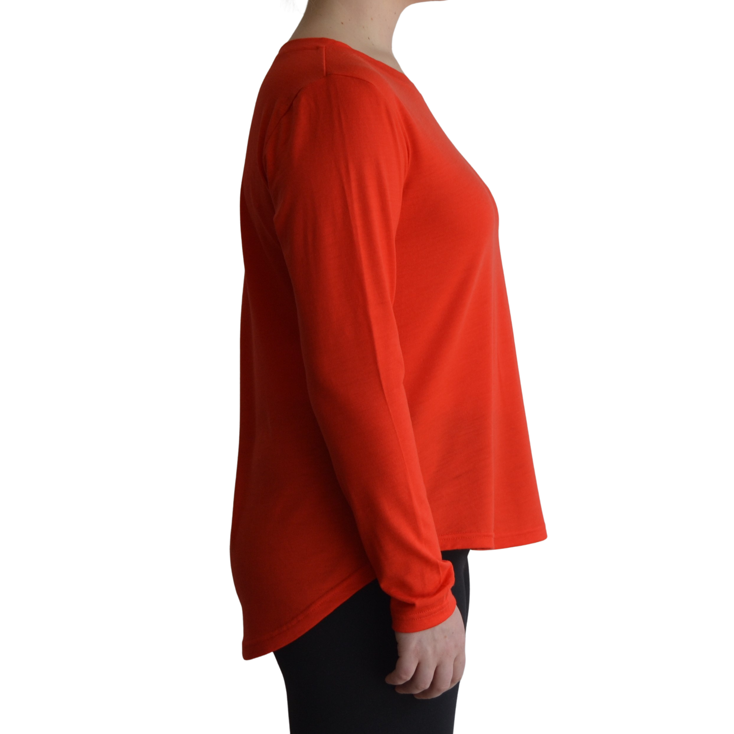 Links long sleeve merino top in mandarin colour, model is standing in profile showing the side view of the shirt with a scooped hemline that drops lower at the back.