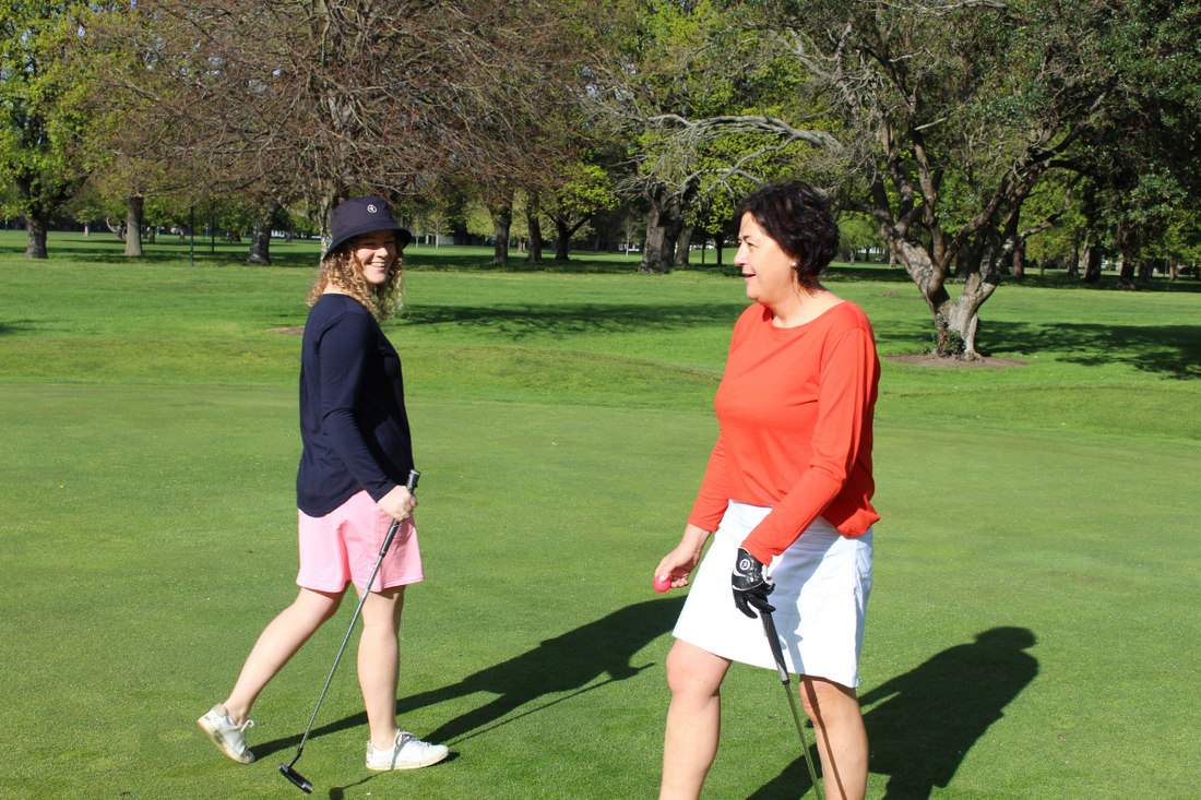 Two women walking past each other on the golf course